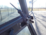Close-up of a car door hinge and wiper arm on a vehicle door, with a parking lot background.