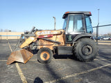 Case backhoe loader in a parking lot with a clear blue sky.