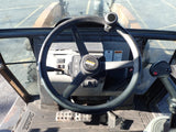 Steering wheel and dashboard of a construction vehicle on a parking lot.